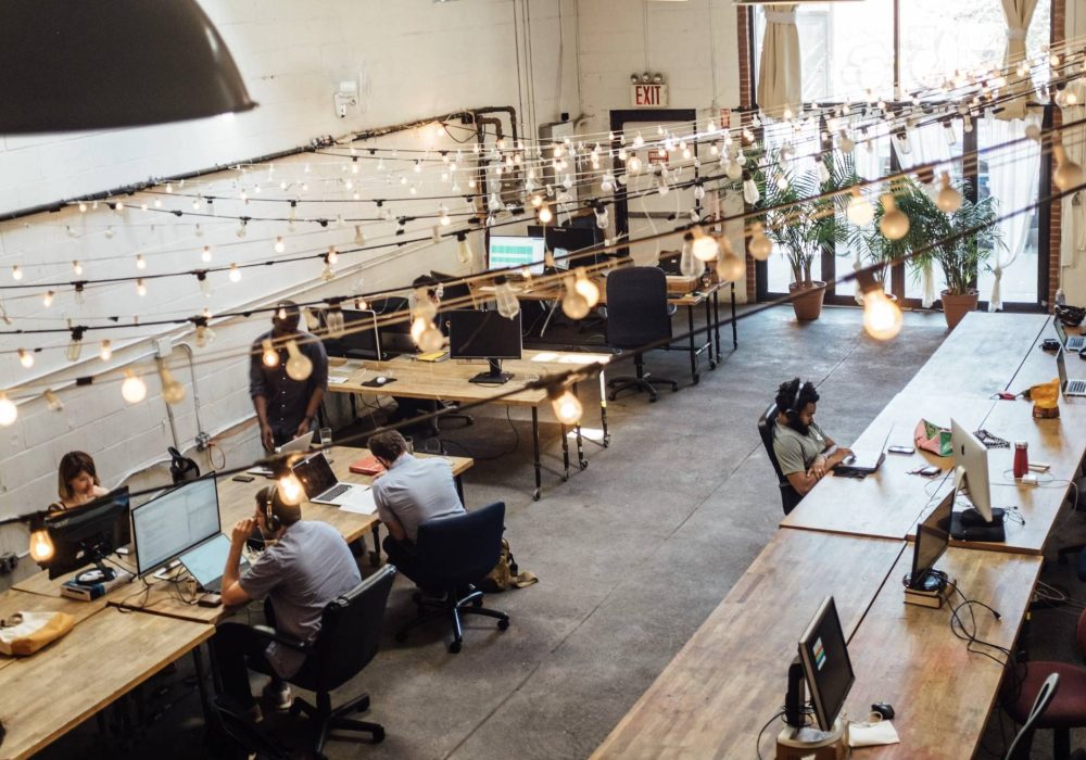 A coworking office layout involving several workstations situated along both sides of the office.